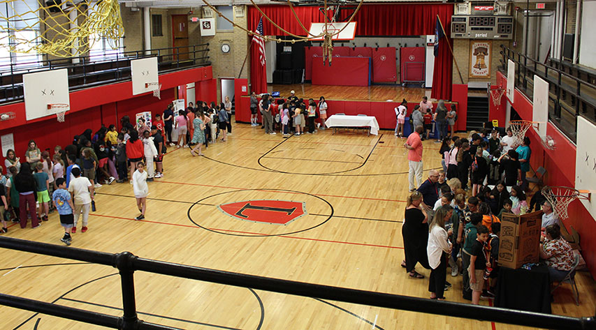 Students visit tables during a career fair in a gymnasium