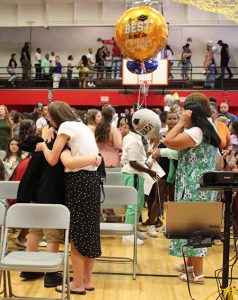 Students and families embrace in congratulations in the gym.