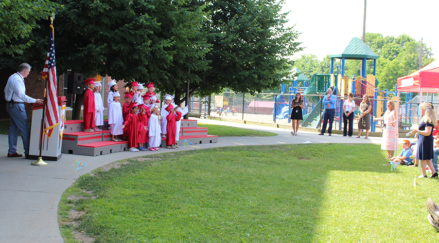 A pre-k graduation ceremony takes place on the lawn
