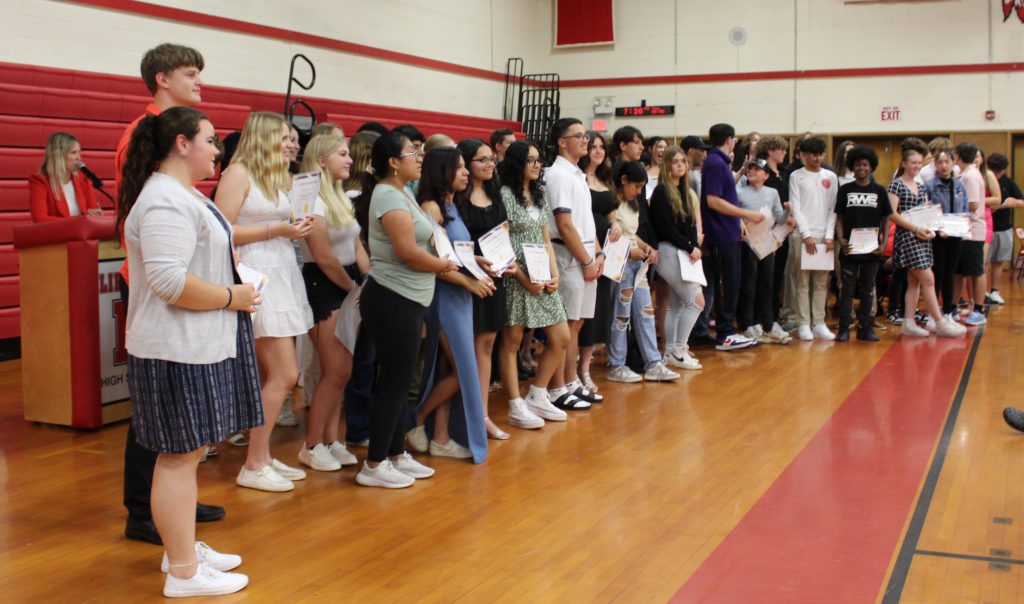 Students stand in a group holding certificates