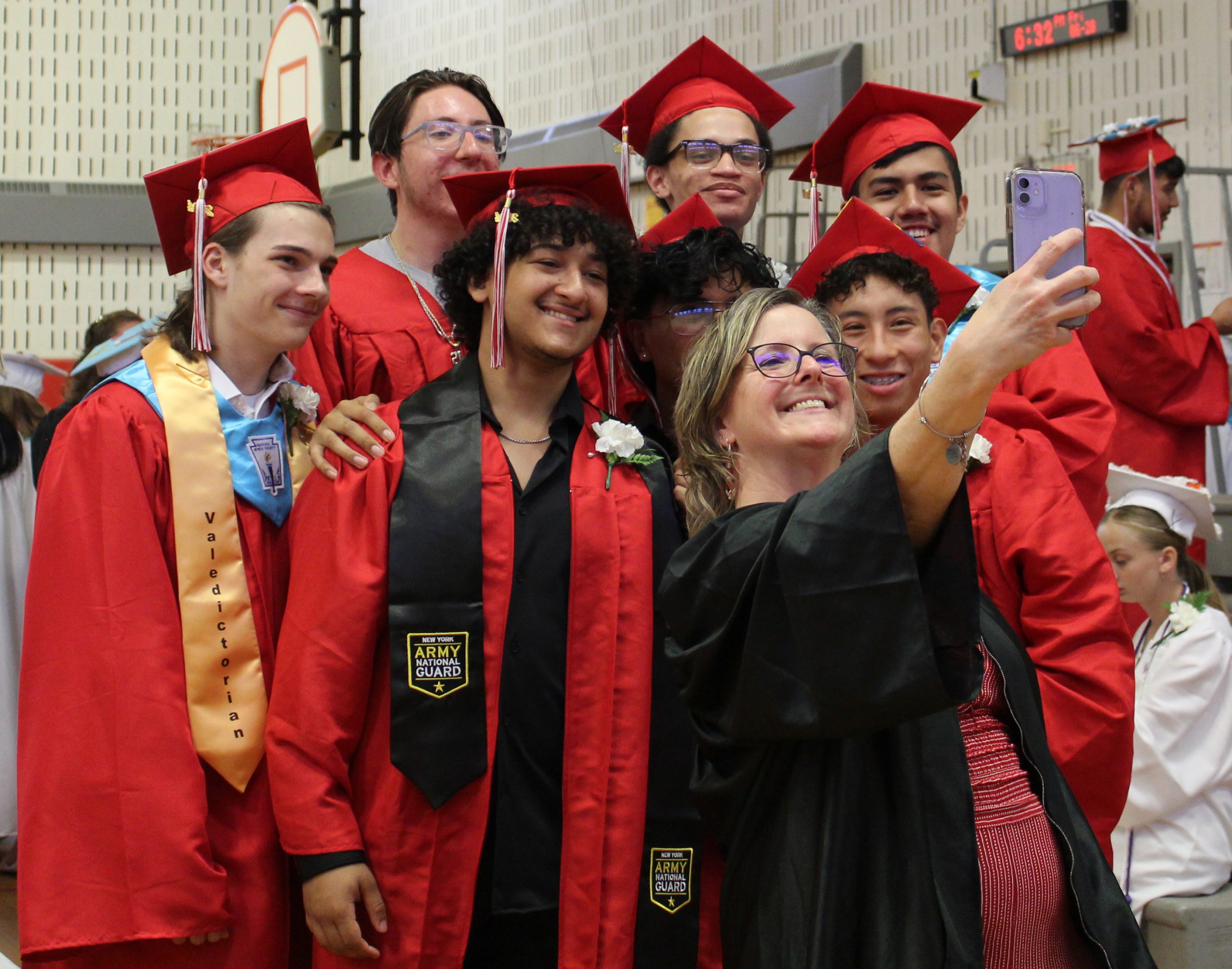 An adult takes a selfie with a group of students.