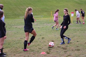 Students practice dribbling a soccer ball