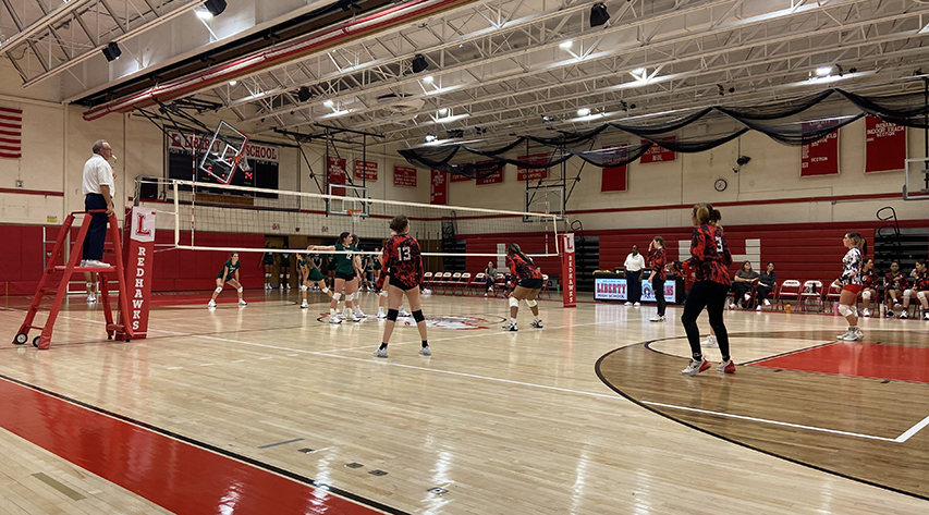 Two volley ball teams await a call on a play