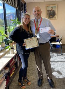 A woman holding a certificate holding a certificate poses with a man holding a piece of paper.