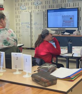 Two adults look at a screen with Specially designed instruction written on it in the InventionLand innovation lab.