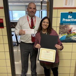 A woman holds a certificate standing next to a man holding a piece of paper.