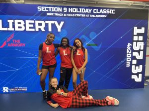 Four girls in Liberty uniforms pose on a stage.