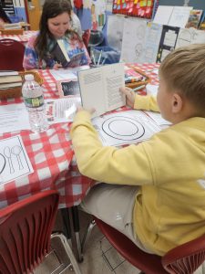 Two students seated at a checkboard table cloth with paper place settings read books