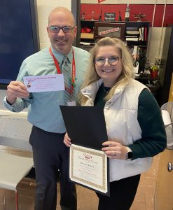 Two people pose with one person holding a piece of paper and another holding a certificate.