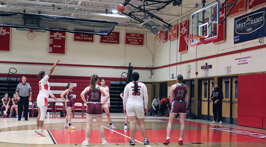 A liberty player in white shoots a foul shot as teammates and opponents stand at the key