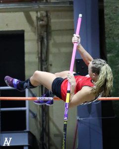 A student clears the bar in pole vault