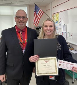 A man stands next to a woman holding a certificate and a paper .