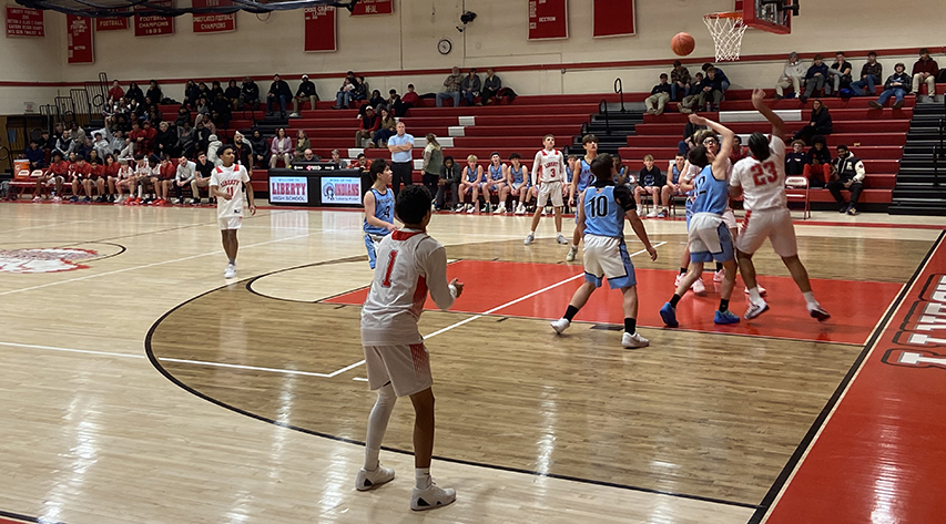 Basketball players go for a rebound after a missed shot